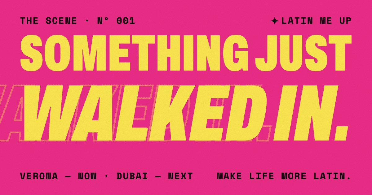 Poster grafico rosa. "SOMETHING JUST" in grandi maiuscole gialle condensate, poi "WALKED IN." in enormi maiuscole gialle corsive con una copia in contorno che entra dal bordo sinistro. Piccolo testo nero: "The Scene · Nº 001", "LATIN ME UP", "Verona — now · Dubai — next", "Make life more Latin."